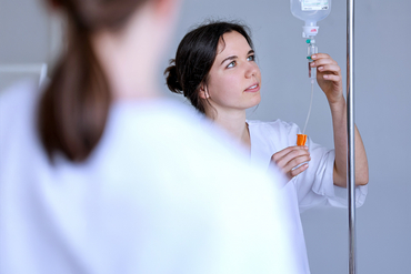 Pflegefachassistentin überprüft eine Infusion.