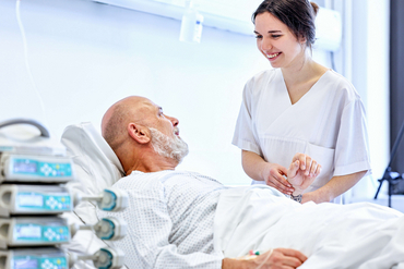 Eine Pflegekraft betreut einen Patienten am Bett